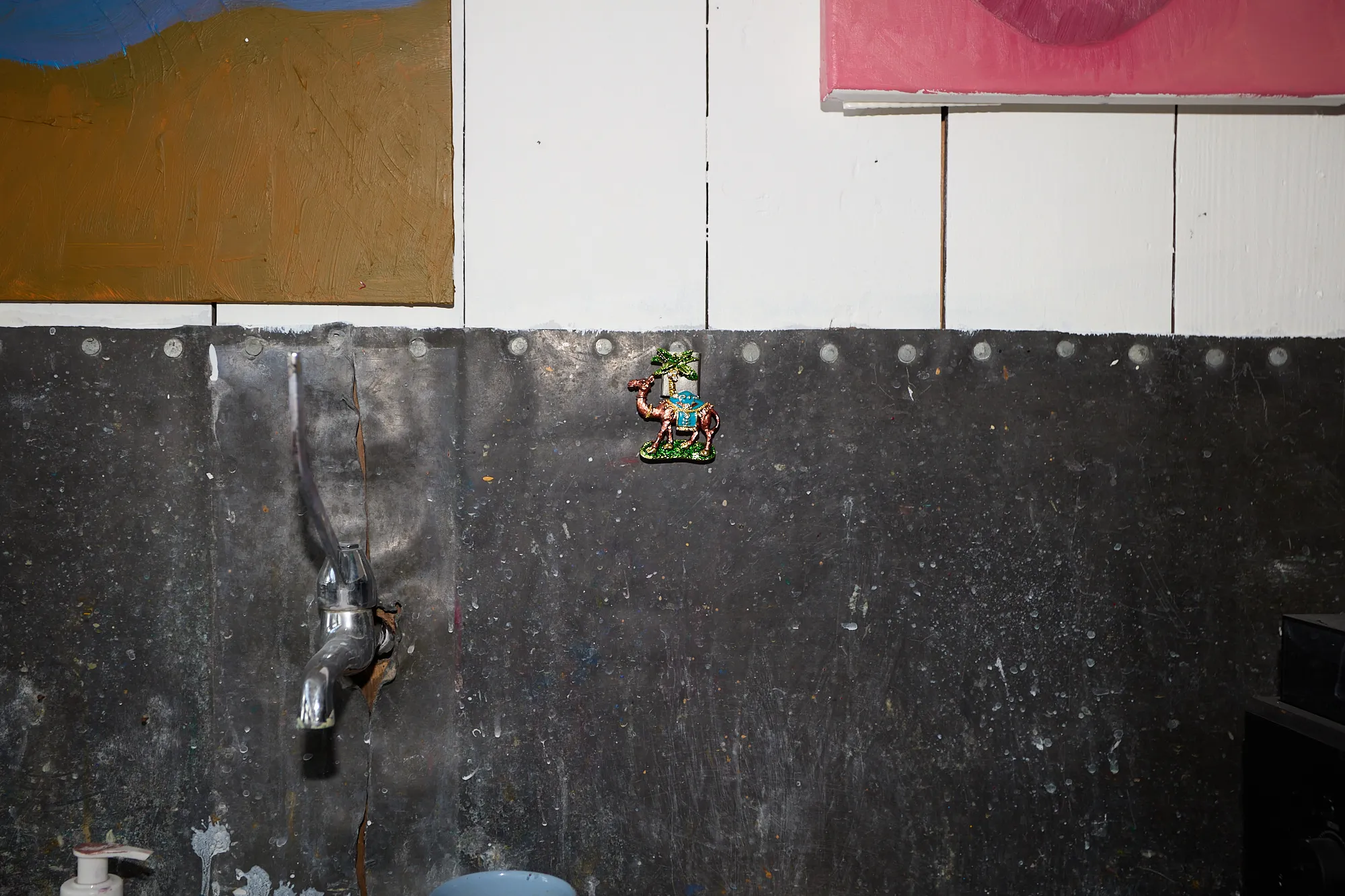 A bare, paint-stained wall in Omar Kholeif's studio, just a tap and a small camel fridge magnet