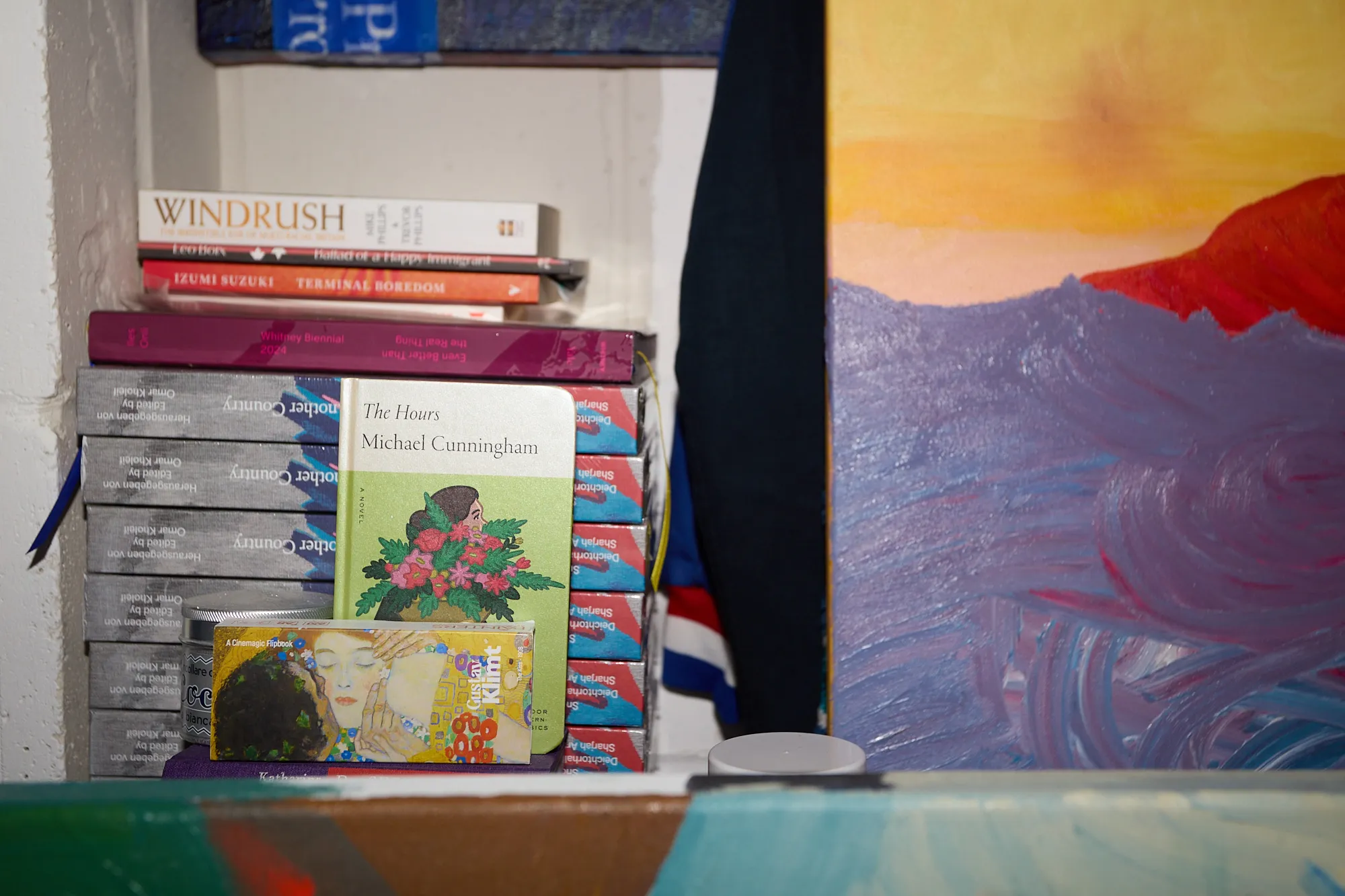 Stacked copies of Another Country, edited by Omar Kholeif, beside other books on a shelf