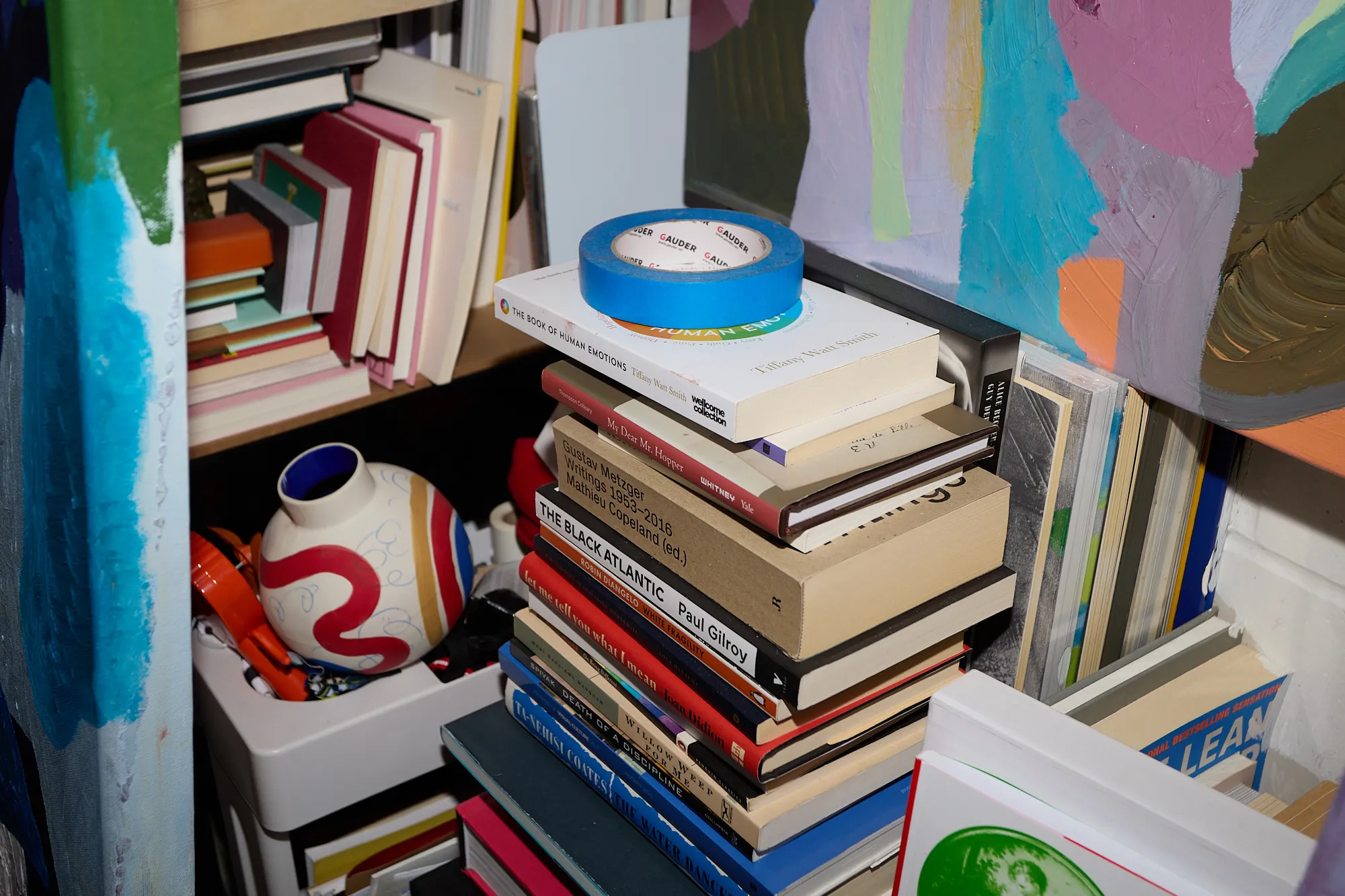 A tall stack of books and a painted vase in Omar Kholeif's studio