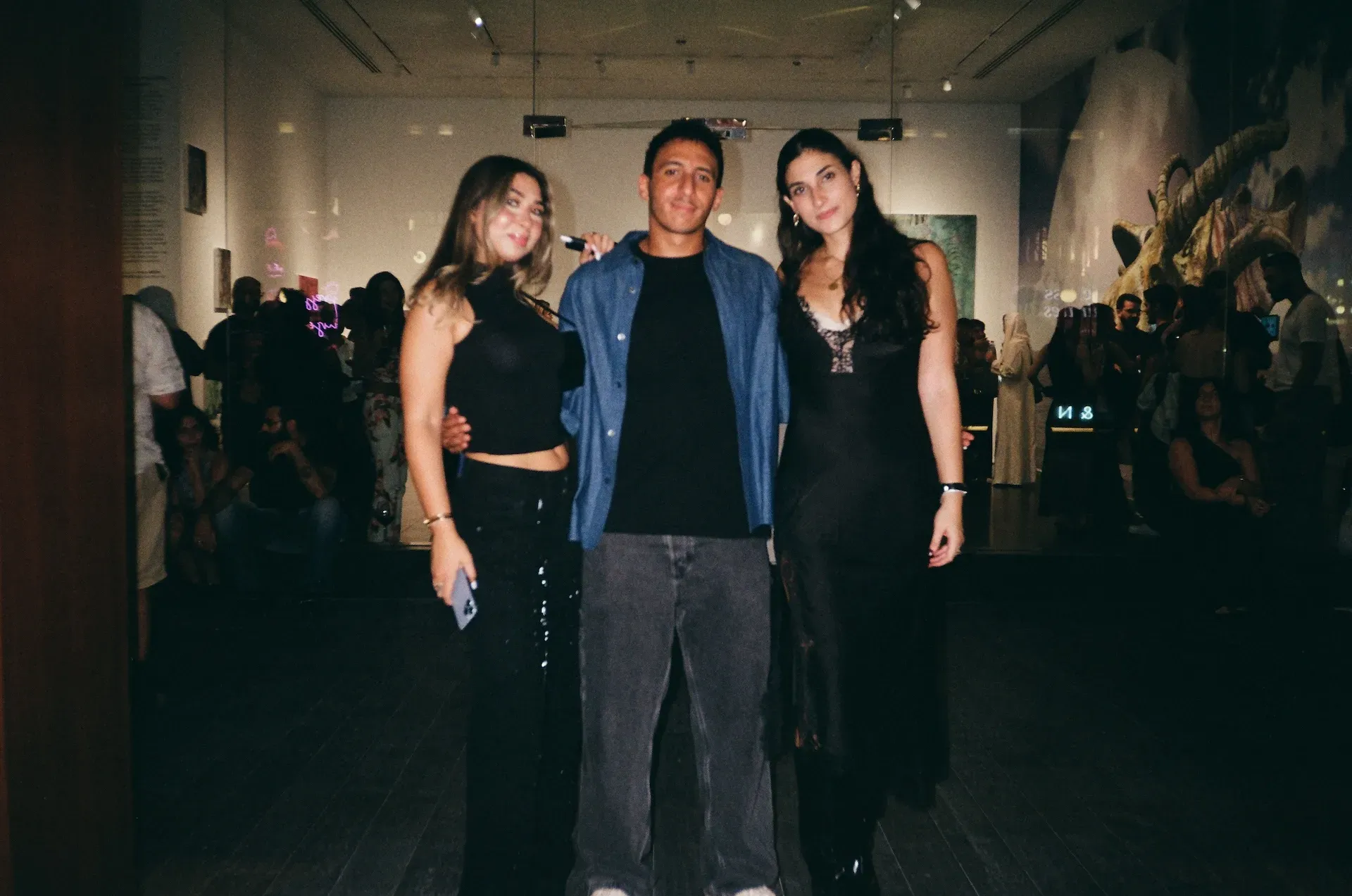 Three guests posing together in the gallery, with a sculptural skull visible behind them